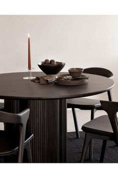 a dining table with two chairs and a bowl of fruit on the plate next to it