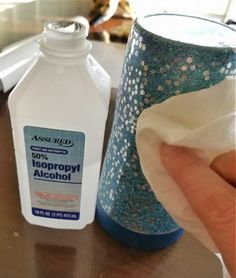 a hand is holding a napkin near a bottle of alcohol on a table with other items in the background