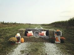 a couch sitting on top of a pile of hay in the middle of a field