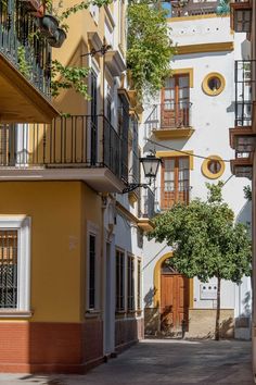 an alley way with several balconies and trees on both sides in the city