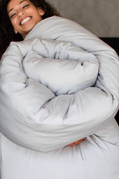 a woman is smiling while wrapped up in a comforter