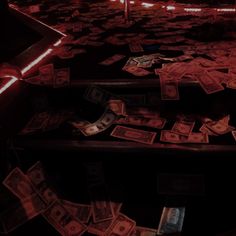 a bunch of money sitting on top of a table next to a red light in the dark