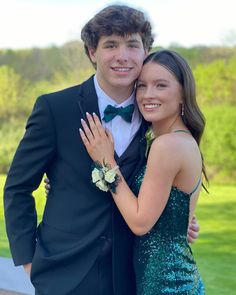 a man in a tuxedo hugging a woman wearing a green sequin dress