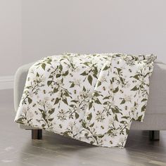 a white and green floral blanket on a couch