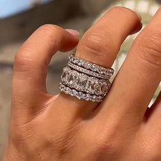 a woman's hand holding two rings with diamonds on top of each one and the other