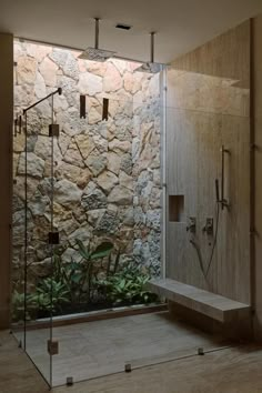 a bathroom with a stone wall and glass shower