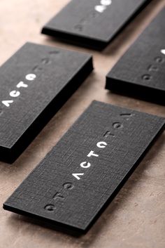 four black business cards with white lettering on the front and back, sitting on a table