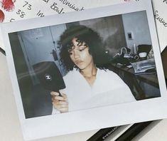 an old photo of a woman holding a cell phone in front of some papers with writing on them