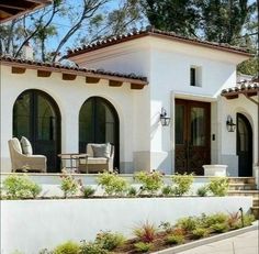 a white house with two chairs on the front porch and an entry way leading to it