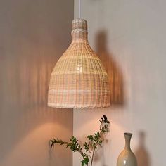 a lamp hanging over a table next to a vase