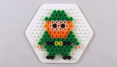 a white plate topped with an orange and green bead art piece on top of a table