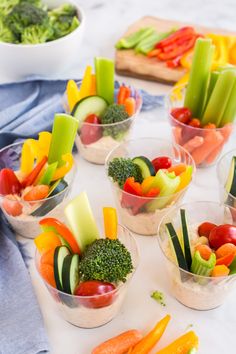 there are many small cups with food in them on the table and one is filled with vegetables