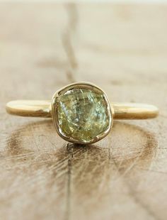 a yellow diamond ring sitting on top of a wooden table