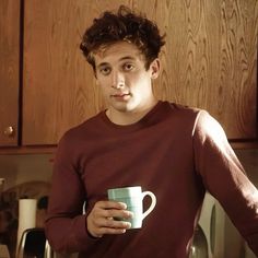 a young man holding a coffee cup in his hands