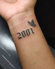 a person with a small tattoo on their wrist that reads 1001 and has a butterfly