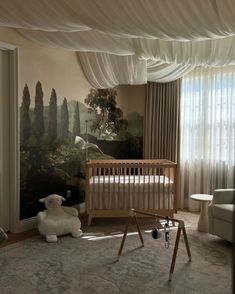 a baby's room with a crib, rocking chair and painting on the wall