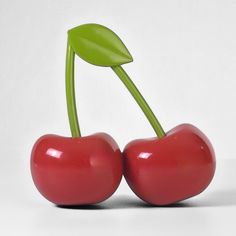 two red cherries with green stems on white background