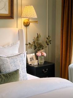 a white bed sitting in a bedroom next to a nightstand with flowers on top of it