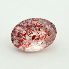 an oval shaped pink and white object on a white surface with red speckles