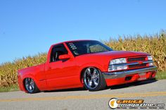 the red truck is parked on the side of the road next to cornfield and blue sky