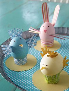 three small plastic birds sitting on top of a blue table cloth covered tray with cupcakes in the shape of bunnies