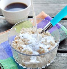 a glass bowl filled with oatmeal next to a cup of coffee