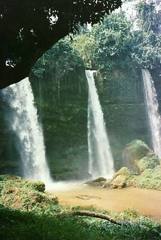 two tall waterfalls in the middle of a forest