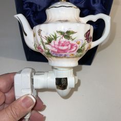 a tea pot is plugged in to a wall outlet with a flowered design on it