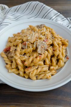 a white plate topped with pasta covered in sauce and cheese on top of a wooden table