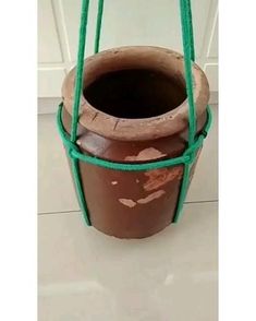 a brown pot with green handles on the floor