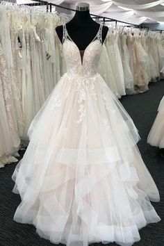 a wedding dress on display at a bridal shop with other dresses in the background