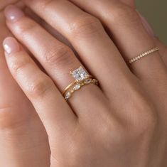 a woman's hand with two gold rings on it and one diamond ring in the middle