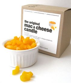 the original mac and cheese candle is in a white bowl next to it's packaging