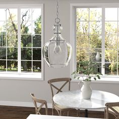 a dining room table with chairs and a vase hanging from it's centerpiece