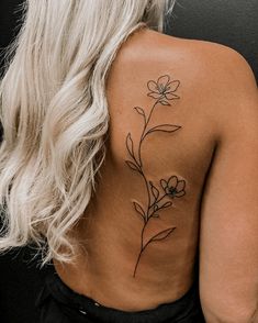 the back of a woman's shoulder with a flower tattoo on her left side