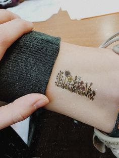 a woman's arm with flowers on it and the word love written in small letters