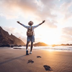 a man walking on the beach with his arms wide open and hands in the air