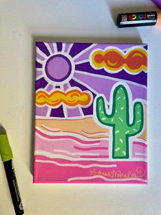 a painting with a cactus on it next to a marker and some crayons