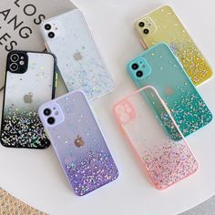 four iphone cases sitting on top of a white table next to a cup and phone case