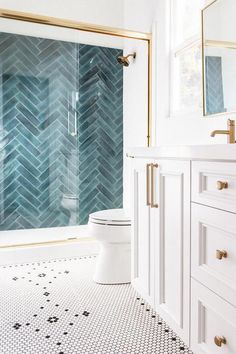 a bathroom with white and blue tiles on the floor, gold trim around the shower