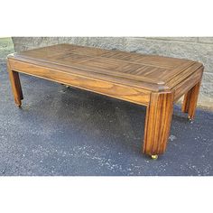 a wooden coffee table sitting on top of a cement floor next to a stone wall