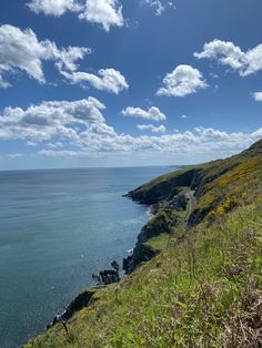 a scenic view of the ocean and cliffs on a sunny day with clouds in the sky