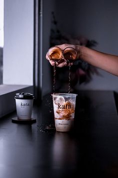 a person pouring coffee into two cups