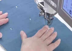 someone is using a sewing machine to sew something on a piece of blue fabric