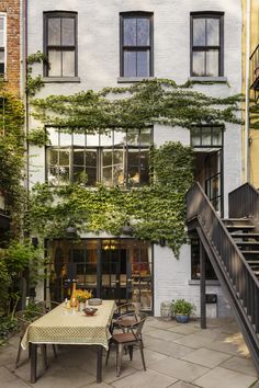 an outdoor dining area with table, chairs and stairs leading up to the upper floor