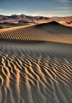 sand dunes in the desert with mountains in the background