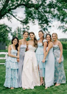 a group of women standing next to each other on top of a lush green field