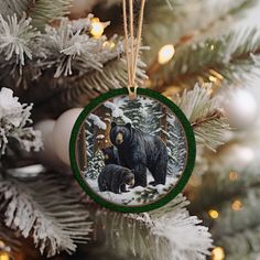 a christmas ornament with two bears on it hanging from a tree in the snow