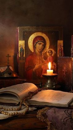 an open book sitting on top of a wooden table next to a candle and pictures