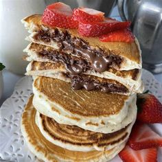 a stack of pancakes with strawberries and chocolate on top